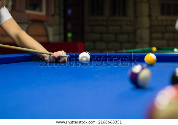 Billiard pool game in progress, player aims to shoot\
balls with cue