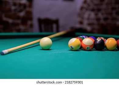 Billiard table with balls, cue ball and cue in the club. table with green cover.