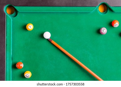 Billiards multicolored balls and cue on billiards green table. Top view.