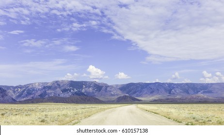 Billings, Montana, USA. View across the foothills of the Bear Tooth Mountains (Rockies) and arid prairie with dirt track in late summer near Billings, Montana, USA.