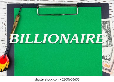 BILLIONAIRE - Word (text), A Dart For Darts And Dollar Bills On A Green Background Of A Notebook, A Wooden White Table. Business Concept: Buying, Selling, Commerce (copy Space).