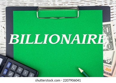 BILLIONAIRE - Word (text) Dollar Bills On Green Background, Pencil, Calculator And Wooden White Table. Business Concept: Buying, Selling, Commerce (copy Space).