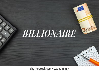 BILLIONAIRE - Word (text) And Euro Money On A Wooden Background, Calculator, Pen And Notepad. Business Concept (copy Space).