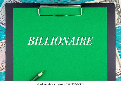 BILLIONAIRE - Word (text) And Money Bills, Dollars On A Green Background Notepad, Pencil, Wooden Table. Business Concept: Buy, Sell, Commerce (copy Space).