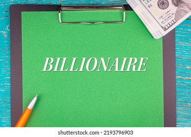 BILLIONAIRE - Word (text) And Money A Pack Of Dollar Bills On A Green Background Notepad, Pen. Business Concept: Buy, Sell (copy Space).