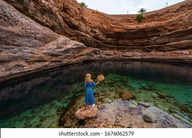 Bimah Oman - October 12, 2019: Sinkhole In Eastern Muscat, Oman. People Swimming In Sinkhole. Woman Model With Her Blue Dress And Hat