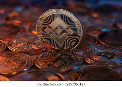 Binance BNB Cryptocurrency Physical Coin placed on crypto altcoins and lit with orange and blue lights. Macro shot. Selective focus. - Shutterstock ID 2157368127
