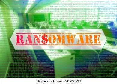 Binary code with the word 'RANSOMWARE' in the center with a blurred background of computer labs.