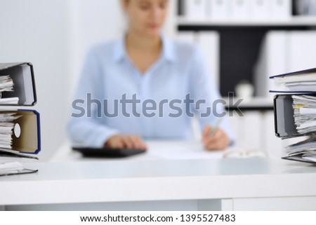 Binders with papers are waiting to be processed by business woman or bookkeeper back in blur. Internal Audit and tax concept