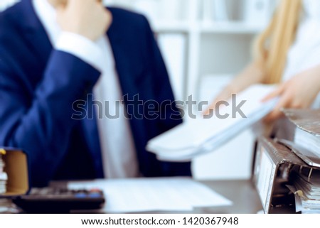 Binders with papers waiting to be processed with businessman or bookkeeper back in blur. Accounting planning budget. Audit, insurance  and business concept