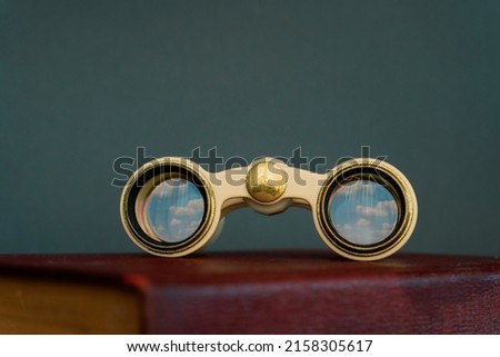 Binocular on a book isolated, cloud reflection on binocular's glass. Dreaming concept, peaceful future.