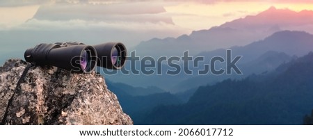 Binocular on top of rock mountain at sunset