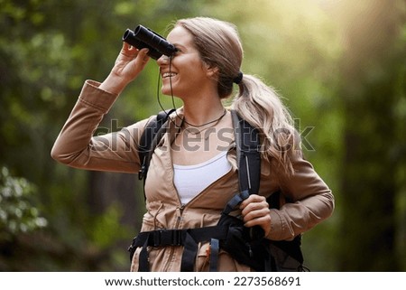 Binoculars, forest and hiking woman for travel journey, jungle adventure and nature explore with backpack and gear. Happy hiker or camper person trekking in woods and search or birdwatching outdoor