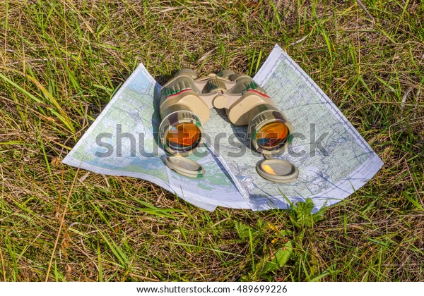 binoculars with maps lying on the grass.\
navigattsiya orienteering tourism travel\
off-road