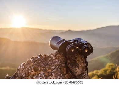 binoculares en la cima de la montaña de roca con un hermoso fondo de puesta de sol.
