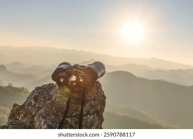 Бинокль на вершине скалы горы красивый фон заката.