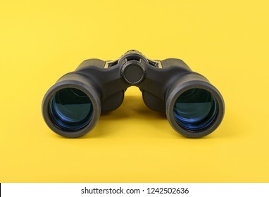 Binoculars on yellow background