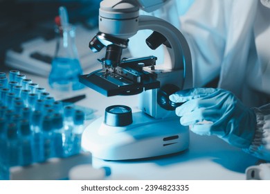 biochemical research scientist working with microscope for coronavirus vaccine development in, Portrait of a Beautiful Female Scientist in Goggles Using Micropipette for Test Analysis. - Powered by Shutterstock