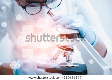biochemical research scientist working with microscope for coronavirus, laboratory glassware containing chemical liquid for design or decorate science, chemistry, biology, medicine and people concept 
