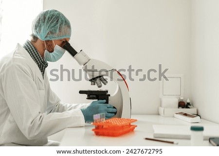 Biochemical research scientist working with microscope in pharmaceutical research labolatory