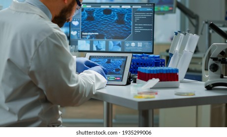 Biochemist checking manifestations of virus looking in tablet with special software in chemistry laboratory. Group of doctors examining vaccine evolution using high tech researching diagnosis