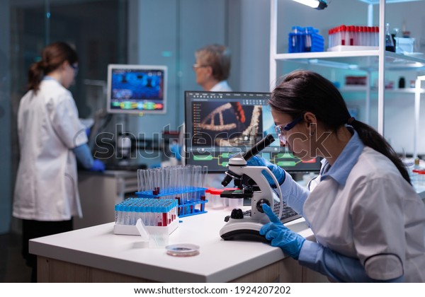 Biochemist\
scientists studying reaction of virus on microscope in laboratory.\
Research chemists working in lab with high tech analyzing blood and\
genetic material samples with special\
program