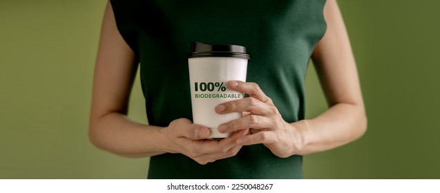 Biodegradable and Compostable Packaging Concept. Closeup of Woman Holding a Hot Cup of Coffee against a Green Wall. Zero Waste Materials. Environment Care, Reuse, Renewable for Sustainable Lifestyle - Powered by Shutterstock