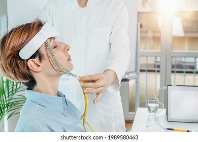 Biofeedback EEG Or Electroencephalograph Training At A Health Center. Therapist Monitoring Brain Waves Using Scalp Sensors Placed Onto A Client’s Head 