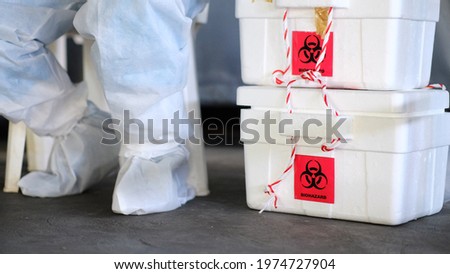 The biohazard box stores a swab test covid-19 and a doctor wearing a PPE protective suit.