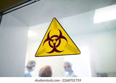 Señal de advertencia de riesgos biológicos en puerta transparente de laboratorio