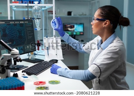 Biologist researcher woman looking at fungi colony using medical petri dish working at genetic disease experiment in biochemistry hospital laboratory. Scientist doctor examining microorganism sample ストックフォト © 