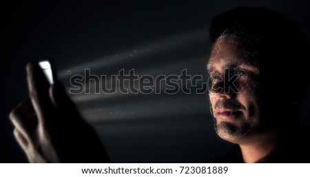 Biometric facial recognition on a smartphone. Male smiling at smartphone as it scans his face