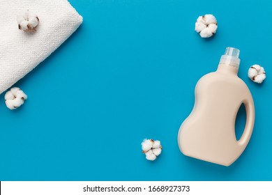 Bioplastic packaging with mockup for label, laundry softener, cotton flowers and clean towels on blue background, copy space