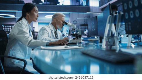 Biotechnology Medical Research Center: Female Asian Neurologist Using Desktop Computer And Talking To Male Caucasian Scientist With Microscope. Doctors Studying Alzheimer's Cases, Finding Solutions. - Powered by Shutterstock