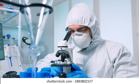 Biotechnology Scientist In Ppe Suit Researching DNA In Laboratory Using Microscope. Team Examining Virus Evolution Using High Tech For Scientific Research Of Vaccine Development Against Covid19