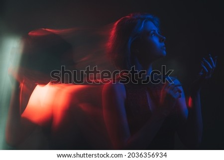 Bipolar disorder. People emotion. Mental stress. Manic syndrome. Woman screaming to calm face expression change in bright red blue neon light color isolated on dark background.