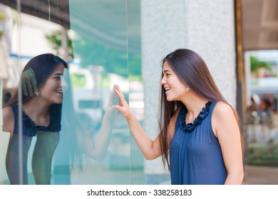 Biracial Asian Cuacasian Teen Girl  Window Shopping In Urban Setting Downtown, Looking In Window With Surprised And Pleased Expression