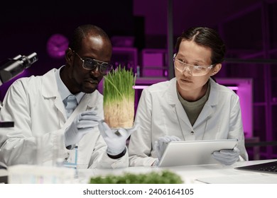 Biracial biologists analyzing herb sample in glassware together in lab - Powered by Shutterstock