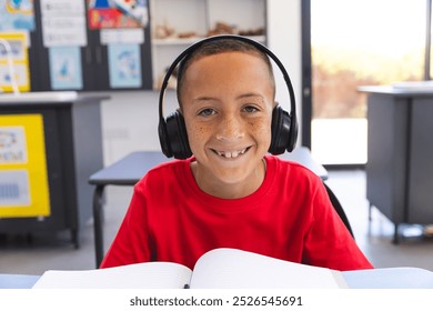 Biracial boy studies in a classroom at school on a video call. He focused on his schoolwork while wearing headphones. - Powered by Shutterstock