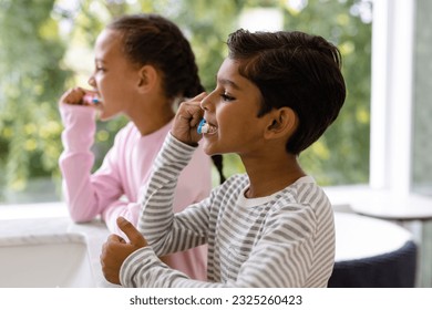 Biracial brother and sister in pyjamas brushing teeth together in the morning in bathroom. Childhood, family, self care, hygiene, healthy living and domestic life, unaltered. - Powered by Shutterstock