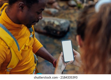 Biracial couple of hikers using smartphone for orientation while hiking in the nature while wearing backpacks with a camping gear - Powered by Shutterstock