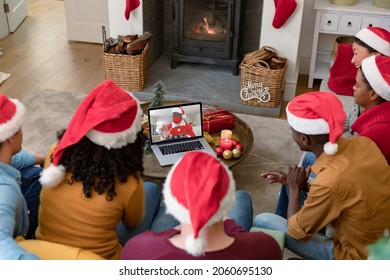 Biracial family in santa hats on christmas laptop video call with friend in face mask. christmas, festivity and communication technology during covid 19 pandemic. - Powered by Shutterstock