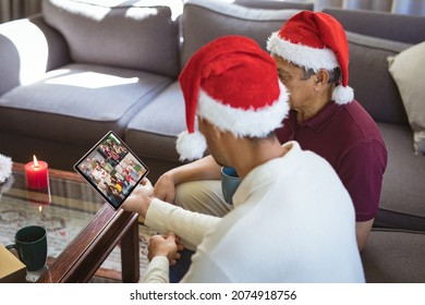 Biracial Father And Adult Son In Santa Hats Making Laptop Christmas Group Video Call With Family. Christmas, Festivity And Communication Technology.