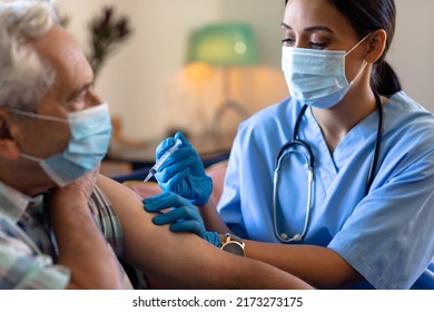 Biracial female health worker giving an injection to caucasian senior man at home. Medical care and retirement senior lifestyle concept
