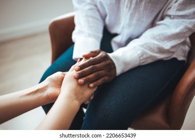 Biracial female psychologist hands holding palms of millennial woman patient. Cropped image of woman comforting her friend. Shot of two unrecognizable women holding hands together 




