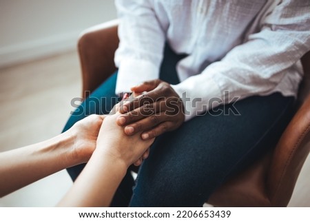 Biracial female psychologist hands holding palms of millennial woman patient. Cropped image of woman comforting her friend. Shot of two unrecognizable women holding hands together 



