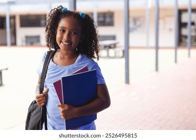 Biracial girl smiling at school, with copy space. She ready for a day of learning with books in hand. - Powered by Shutterstock