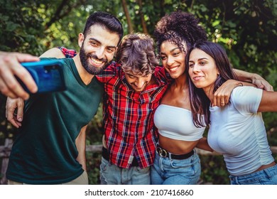 A biracial group of best friends joke together by taking selfies in the countryside - Powered by Shutterstock