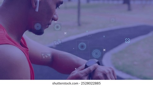 Biracial man checking smartwatch during outdoor workout. He has short black hair, wearing red tank top, and focusing on fitness tracker - Powered by Shutterstock