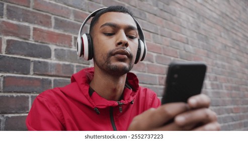 Biracial man wearing headphones, using smartphone in the street. backpacking holiday city travel break. - Powered by Shutterstock